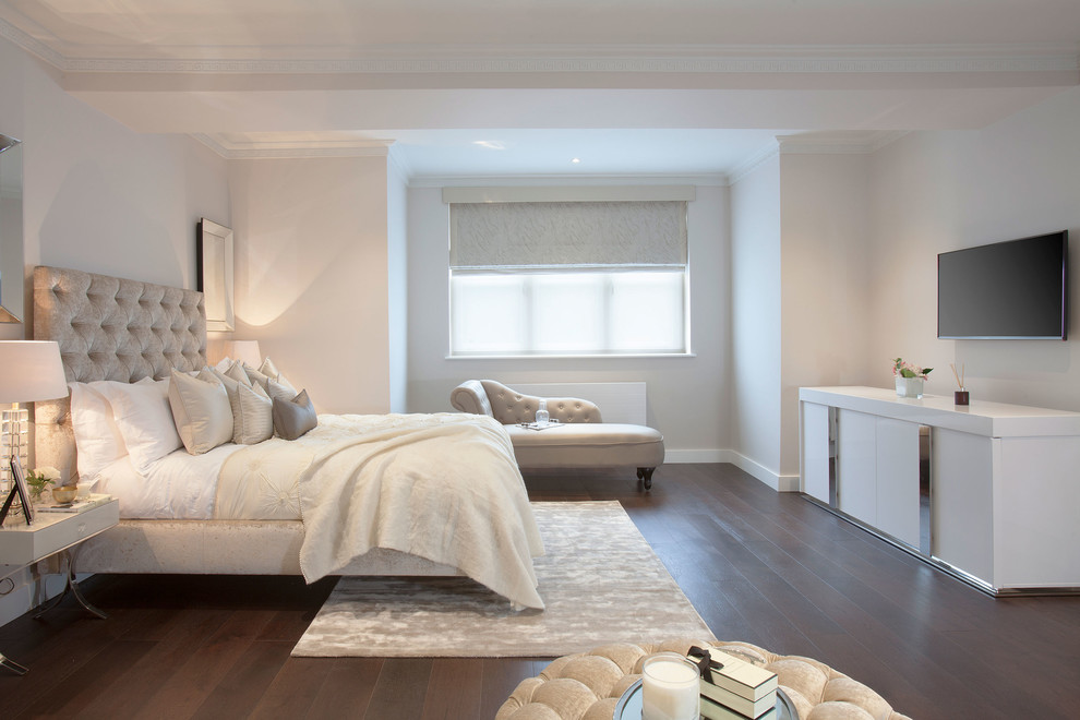 This is an example of a transitional master bedroom in London with white walls and dark hardwood floors.