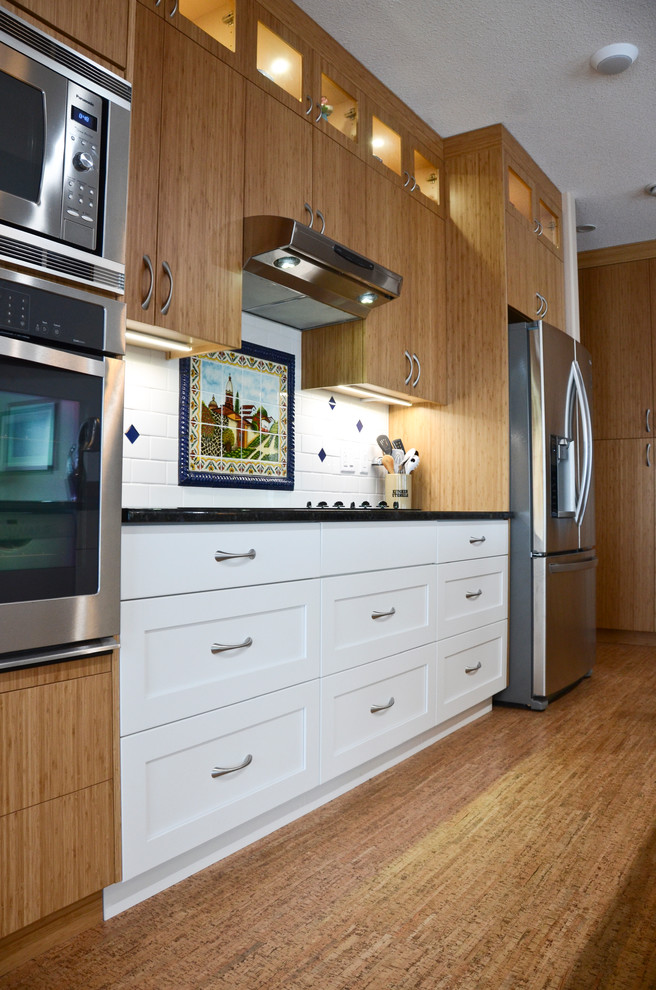 Large transitional single-wall cork floor open concept kitchen photo in Edmonton with an undermount sink, flat-panel cabinets, medium tone wood cabinets, granite countertops, white backsplash, ceramic backsplash, stainless steel appliances and an island