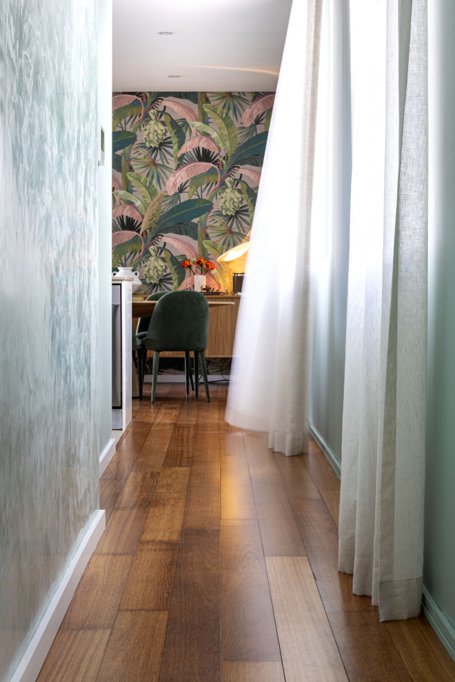 This is an example of a small tropical hallway in Sydney with green walls, medium hardwood floors and brown floor.