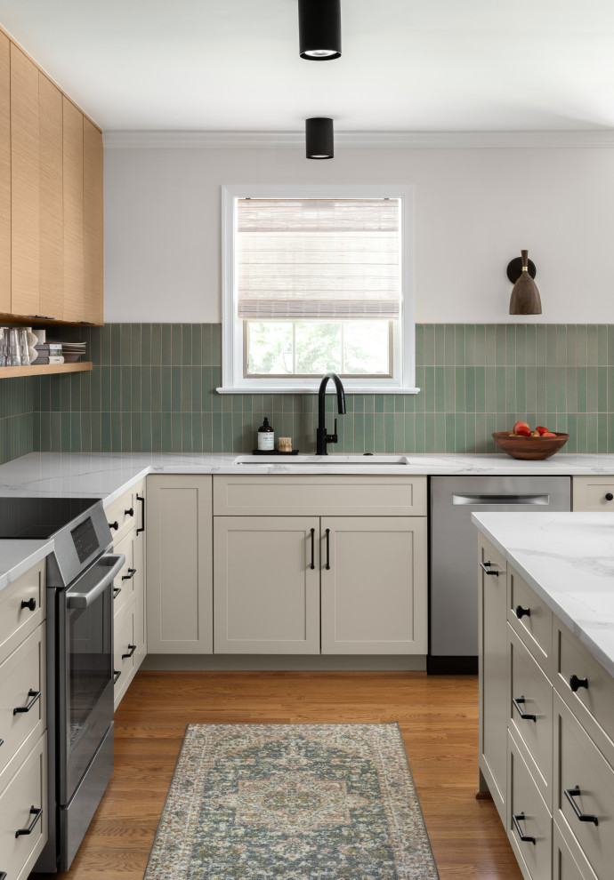 Small midcentury l-shaped kitchen/diner in DC Metro with a submerged sink, flat-panel cabinets, light wood cabinets, engineered stone countertops, green splashback, ceramic splashback, stainless steel appliances, medium hardwood flooring, an island, brown floors and white worktops.