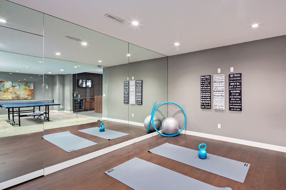 This is an example of a mid-sized transitional home yoga studio in Calgary with grey walls and brown floor.