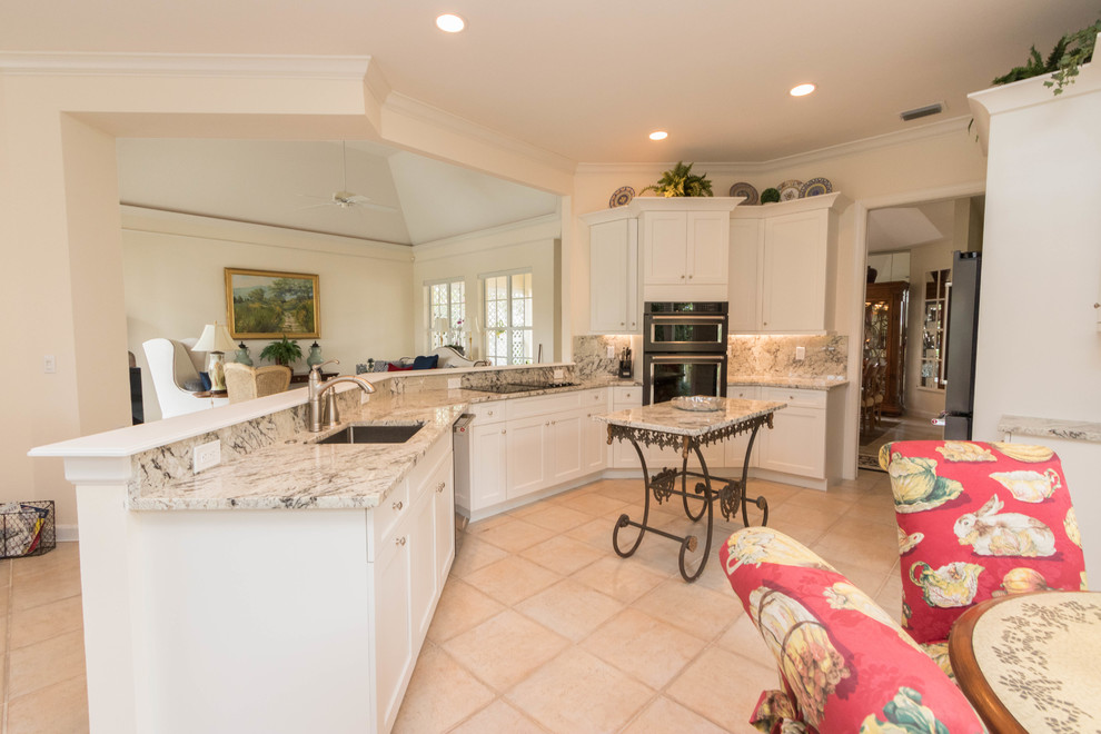 Inspiration for a large transitional porcelain tile eat-in kitchen remodel in Miami with an undermount sink, shaker cabinets, white cabinets, granite countertops, gray backsplash, stone slab backsplash, black appliances and an island