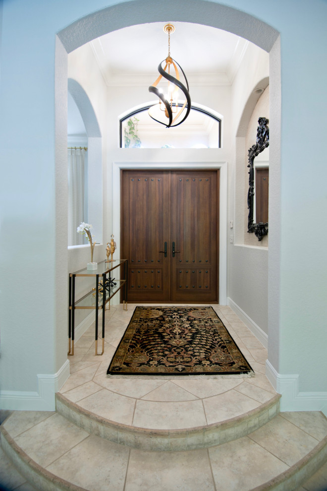 Eklektisk inredning av en liten foajé, med grå väggar, travertin golv, en dubbeldörr, en brun dörr och beiget golv
