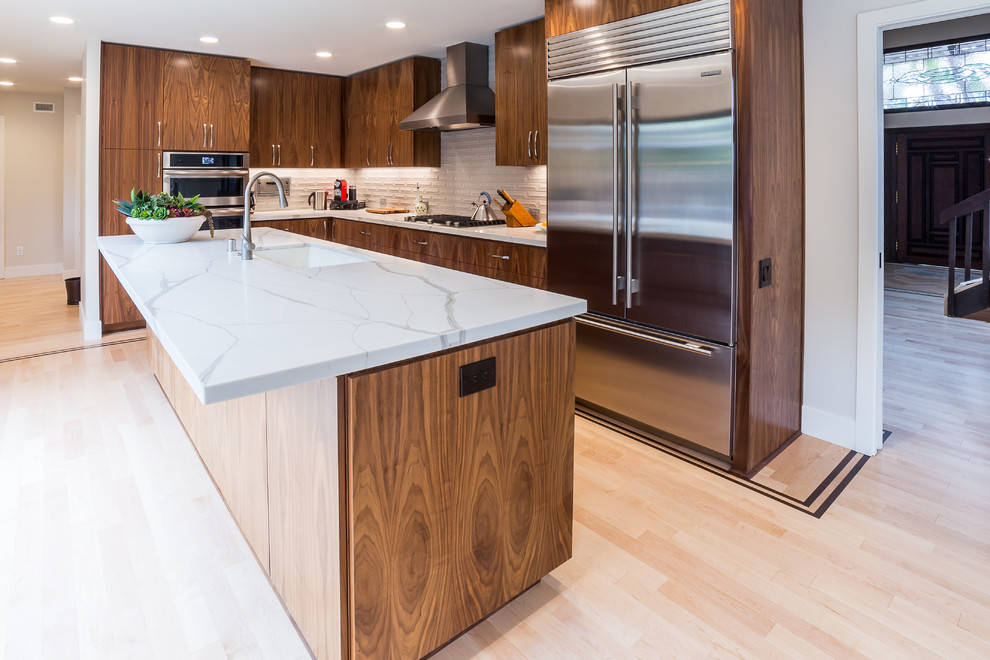 Inspiration for a large contemporary l-shaped eat-in kitchen in San Diego with an undermount sink, shaker cabinets, medium wood cabinets, granite benchtops, white splashback, ceramic splashback, stainless steel appliances, light hardwood floors, with island, brown floor and white benchtop.