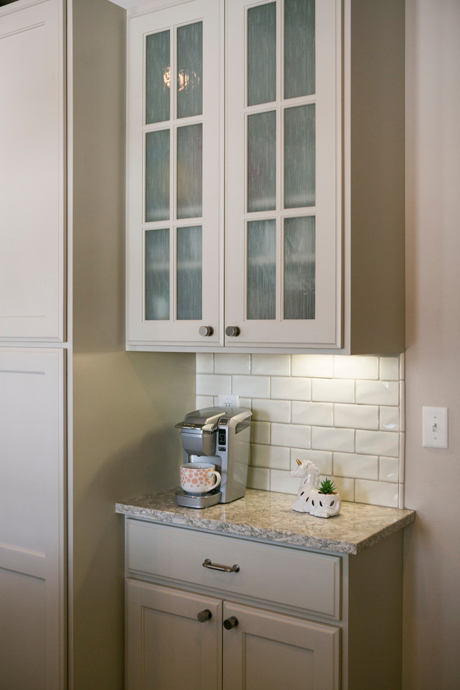 Open concept kitchen - mid-sized rustic l-shaped open concept kitchen idea with raised-panel cabinets, white cabinets, granite countertops, white backsplash, subway tile backsplash, stainless steel appliances, an island and gray countertops