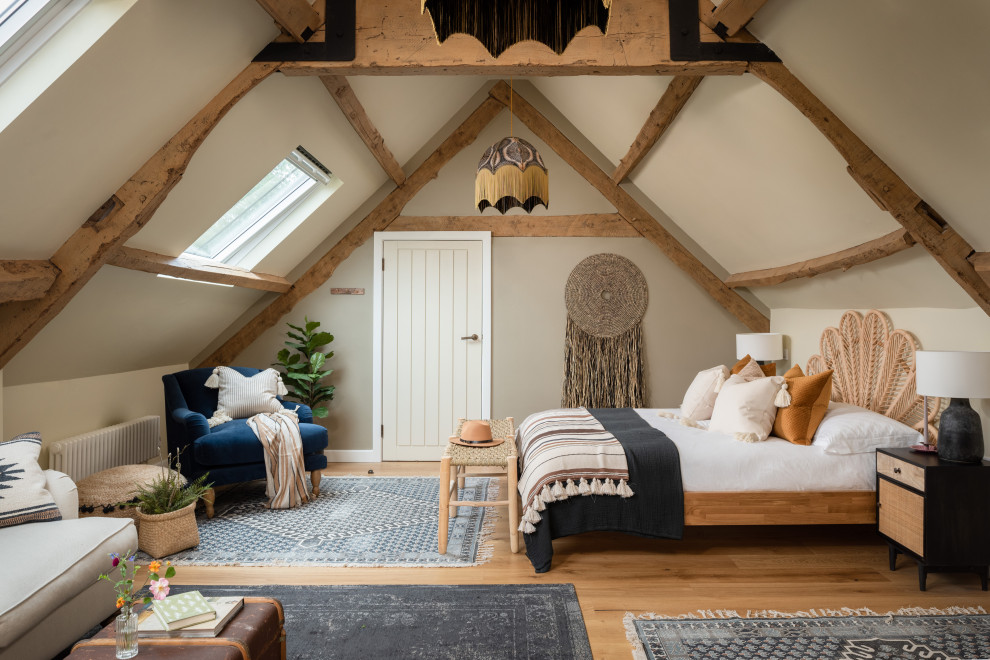 Example of a large cottage medium tone wood floor and brown floor bedroom design in Gloucestershire with beige walls