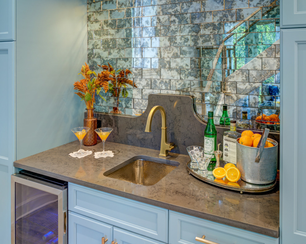 Inspiration for a mid-sized transitional single-wall and walk-out brown floor and porcelain tile basement remodel with an undermount sink, blue cabinets, multicolored backsplash, mirror backsplash, gray countertops, recessed-panel cabinets, quartz countertops, a bar and white walls