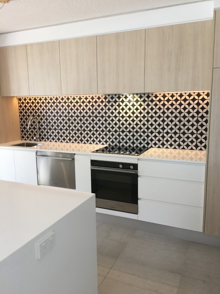 Inspiration for a beach style eat-in kitchen in Sunshine Coast with an undermount sink, flat-panel cabinets, multi-coloured splashback, ceramic splashback, stainless steel appliances, porcelain floors and with island.