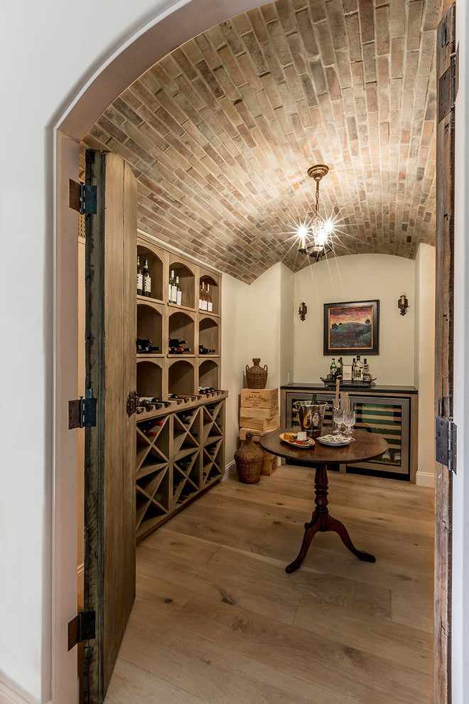 Design ideas for a mediterranean wine cellar in San Diego with light hardwood floors, diamond bins and beige floor.
