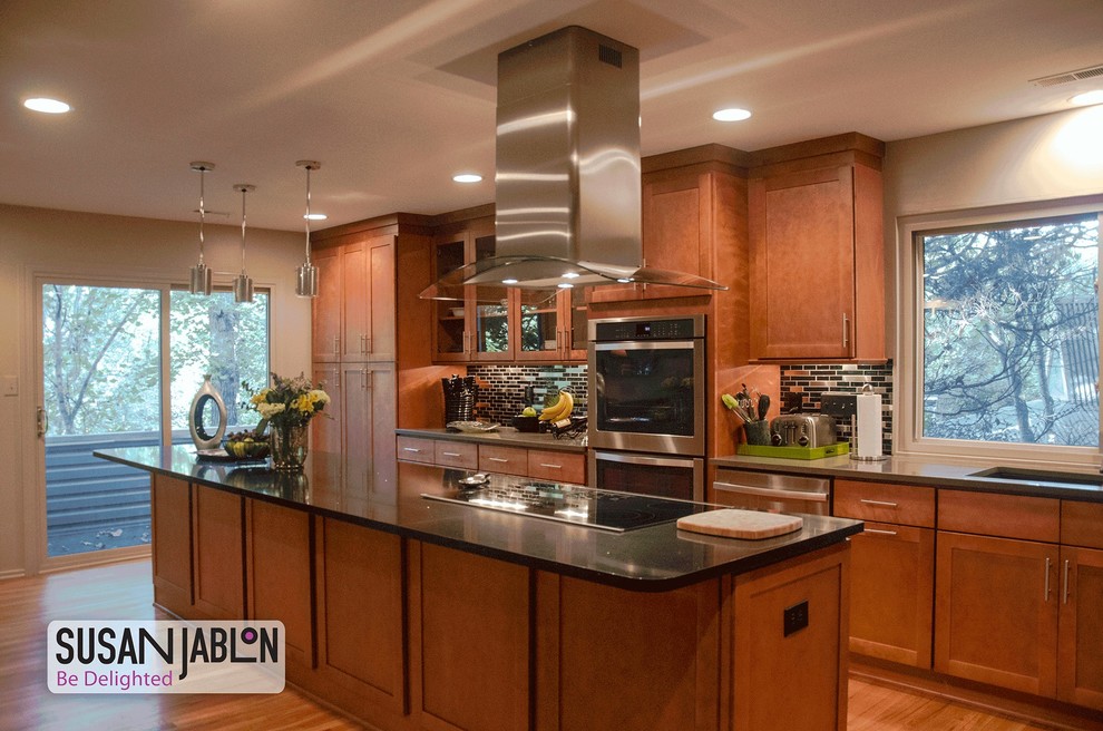 Design ideas for a large contemporary l-shaped eat-in kitchen in New York with metallic splashback, metal splashback, a drop-in sink, flat-panel cabinets, medium wood cabinets, solid surface benchtops, stainless steel appliances, medium hardwood floors, with island and brown floor.