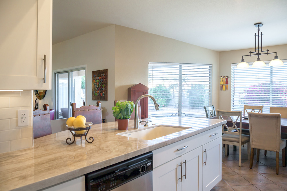Transitional galley ceramic tile open concept kitchen photo in Phoenix with an undermount sink, recessed-panel cabinets, white cabinets, quartz countertops, white backsplash, ceramic backsplash, stainless steel appliances and an island