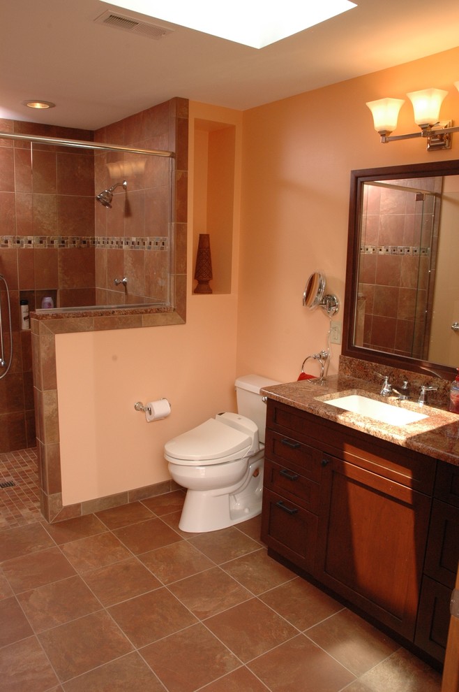 Design ideas for a mid-sized traditional master bathroom in Cincinnati with furniture-like cabinets, dark wood cabinets, a curbless shower, a two-piece toilet, beige tile, brown tile, multi-coloured tile, ceramic tile, orange walls, ceramic floors, an undermount sink, granite benchtops, brown floor and an open shower.