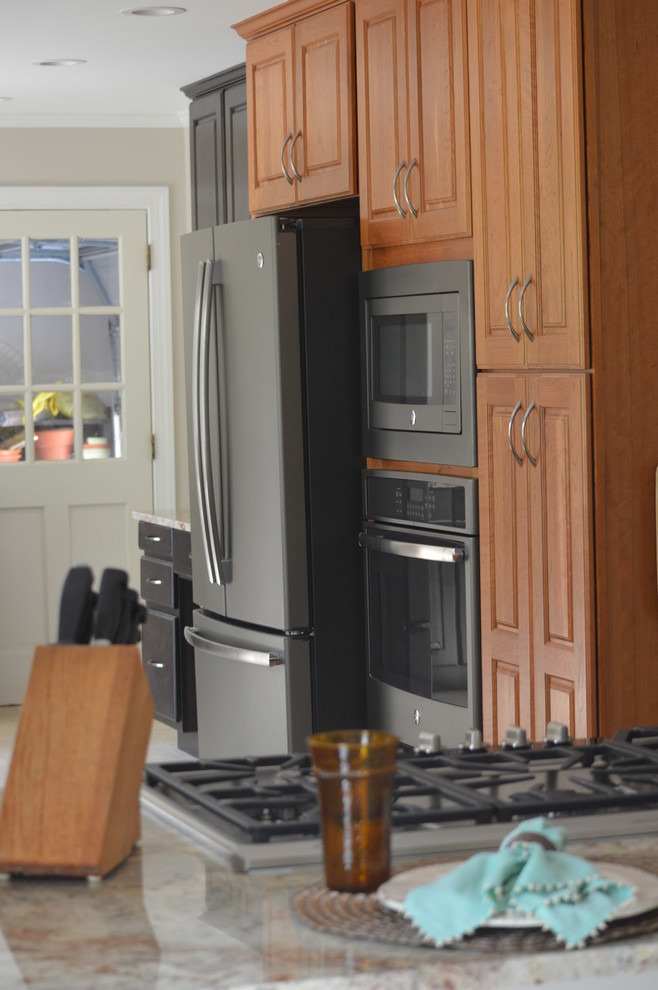 Eat-in kitchen - large transitional l-shaped porcelain tile and beige floor eat-in kitchen idea with a farmhouse sink, raised-panel cabinets, brown cabinets, granite countertops, white backsplash, ceramic backsplash, stainless steel appliances and a peninsula