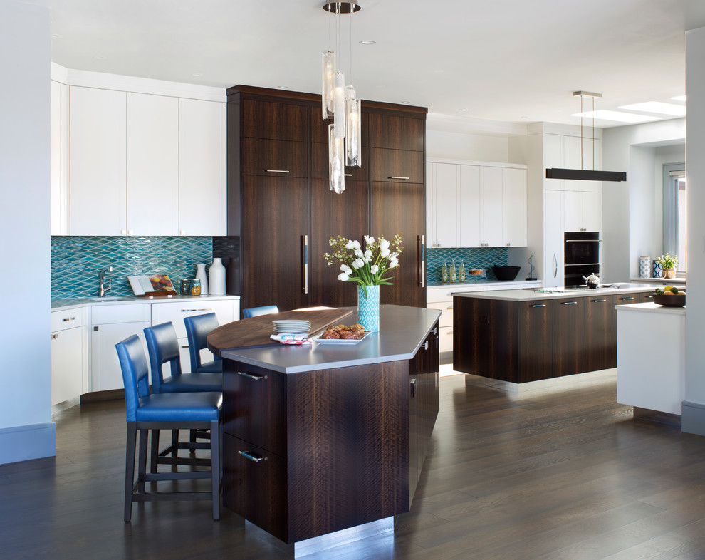 This is an example of a contemporary u-shaped eat-in kitchen in Denver with flat-panel cabinets, dark wood cabinets, blue splashback, ceramic splashback, black appliances, dark hardwood floors, multiple islands and grey benchtop.