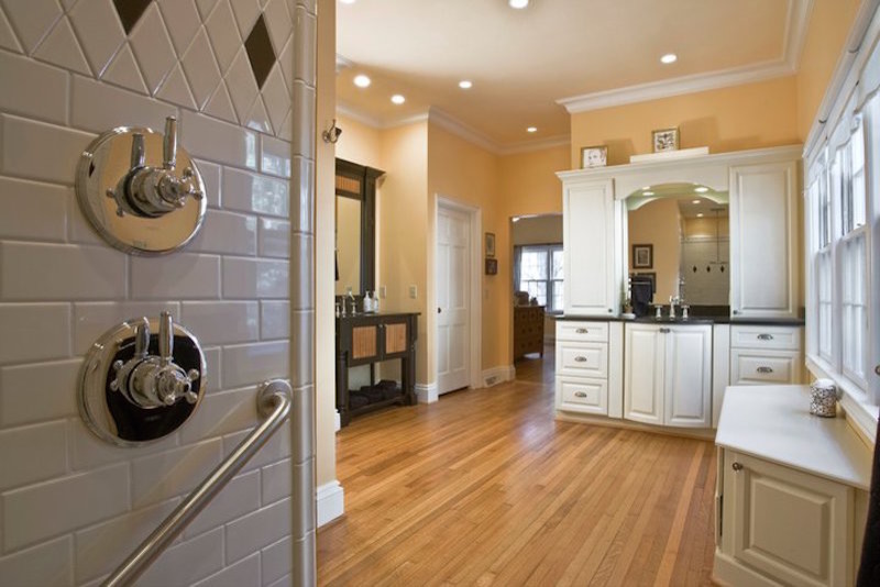 This is an example of a mid-sized traditional master bathroom in Other with raised-panel cabinets, white cabinets, an alcove shower, a two-piece toilet, black tile, black and white tile, white tile, porcelain tile, yellow walls, medium hardwood floors, an undermount sink, engineered quartz benchtops, brown floor and an open shower.