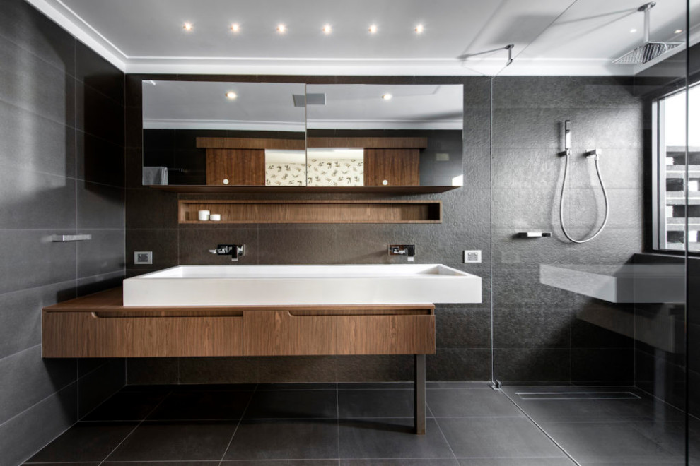 This is an example of a large industrial bathroom in Perth with flat-panel cabinets, medium wood cabinets, a double shower, gray tile, ceramic tile, grey walls, cement tiles, grey floor, an open shower, a double vanity and a floating vanity.