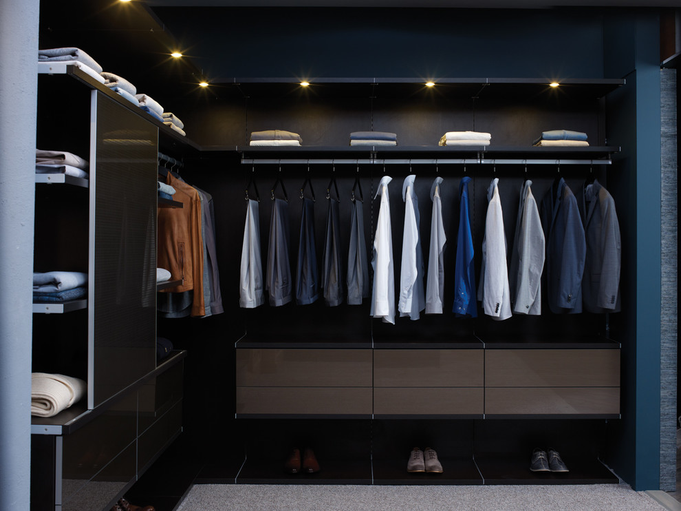This is an example of a mid-sized modern men's walk-in wardrobe in Nashville with flat-panel cabinets, brown cabinets and carpet.