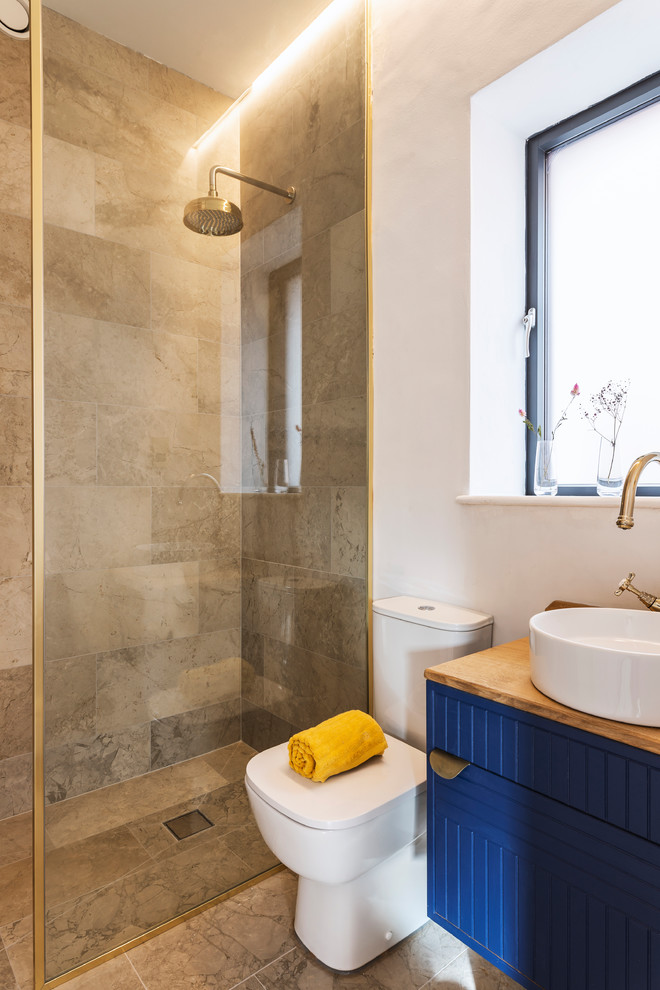 Photo of a transitional master bathroom in Manchester with blue cabinets, a curbless shower, porcelain tile, white walls, marble floors, wood benchtops and an open shower.