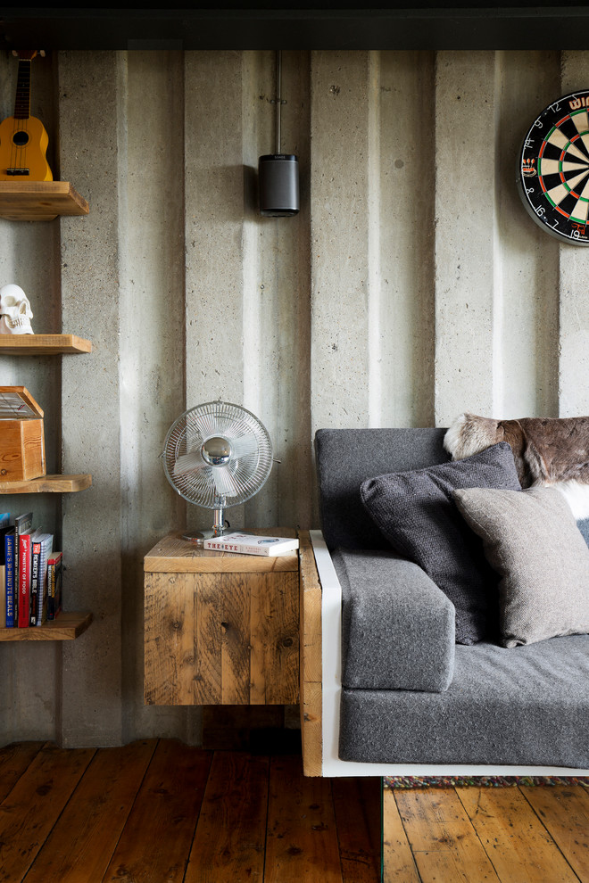 This is an example of a small industrial living room in London with medium hardwood floors and grey walls.