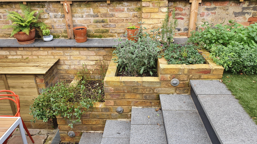 Photo of a small contemporary backyard garden for summer in London with brick pavers and a wood fence.