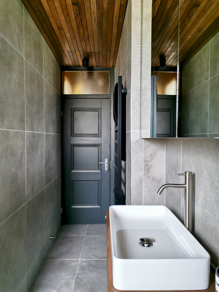 This is an example of a small contemporary grey and brown bathroom in Other with flat-panel cabinets, brown cabinets, a built-in bath, a shower/bath combination, a wall mounted toilet, grey tiles, porcelain tiles, grey walls, porcelain flooring, grey floors, a single sink, a floating vanity unit and a timber clad ceiling.