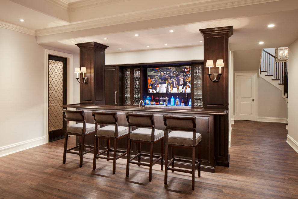 Design ideas for a traditional galley wet bar in Chicago with raised-panel cabinets, dark wood cabinets, wood benchtops, medium hardwood floors, brown floor and brown benchtop.