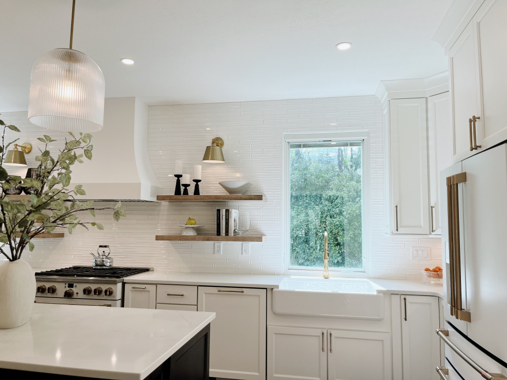Eat-in kitchen - large transitional l-shaped light wood floor and beige floor eat-in kitchen idea with a farmhouse sink, shaker cabinets, white cabinets, quartz countertops, white backsplash, ceramic backsplash, white appliances, an island and white countertops