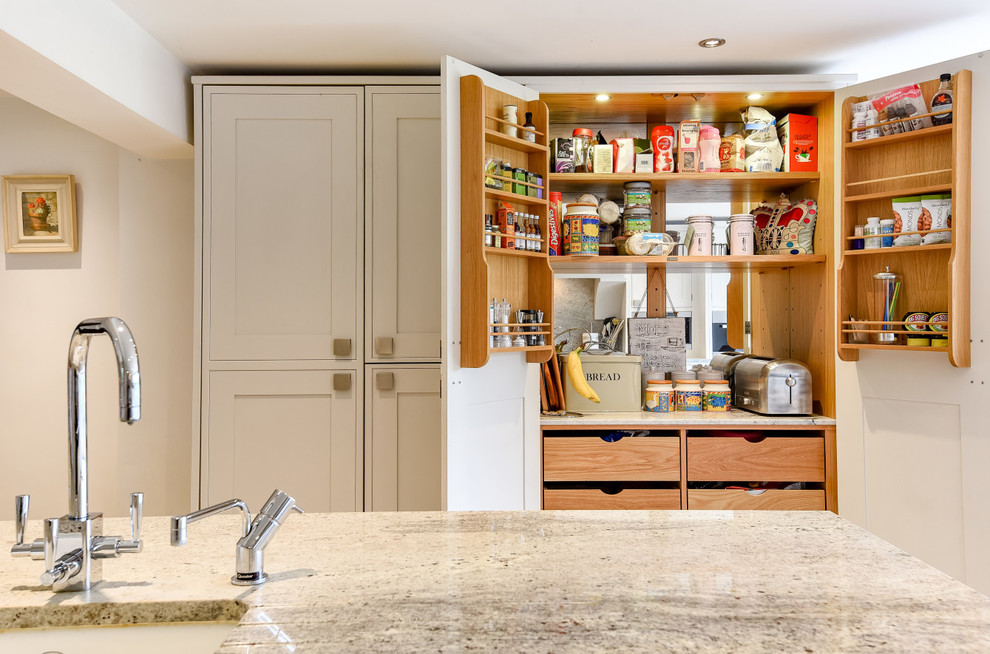 Design ideas for a mid-sized traditional galley eat-in kitchen in Berkshire with a drop-in sink, shaker cabinets, white cabinets, granite benchtops, white splashback, stone slab splashback, panelled appliances and with island.