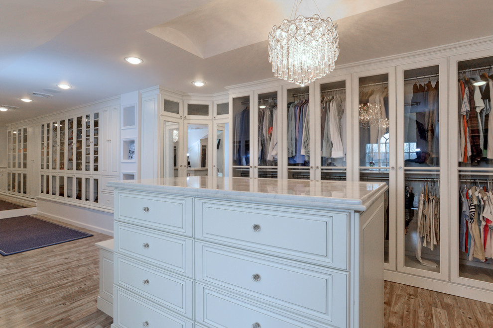 Photo of a traditional dressing room in New York with white cabinets and light hardwood floors.