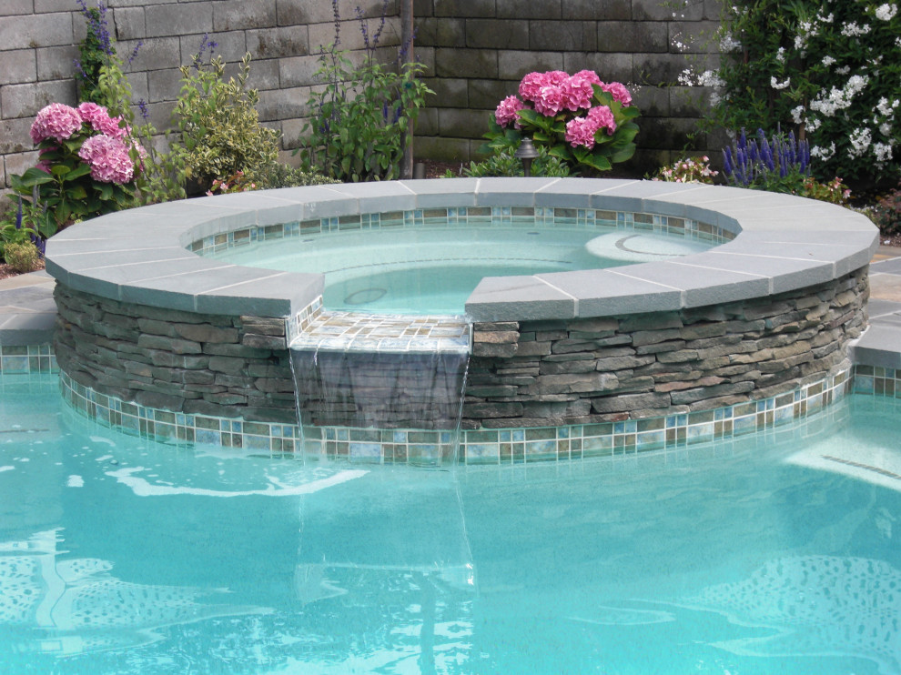 Mid-sized traditional backyard kidney-shaped natural pool in Los Angeles with a water feature and natural stone pavers.