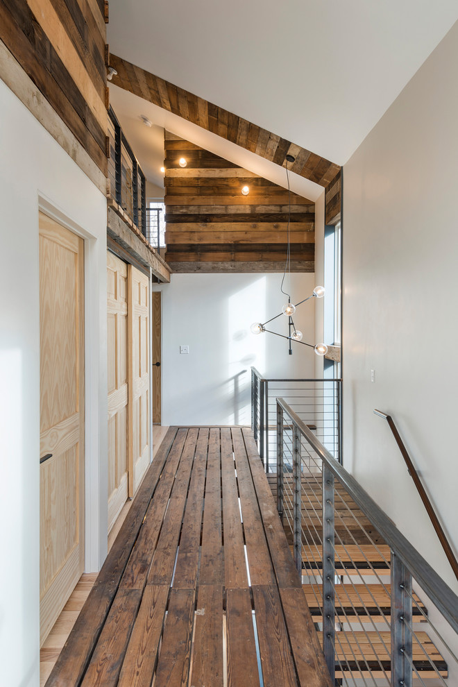 Design ideas for an industrial hallway in Providence with white walls, dark hardwood floors and brown floor.