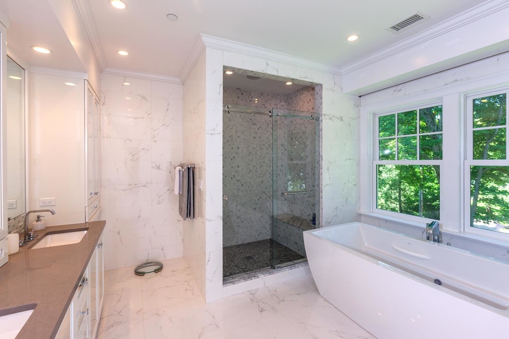 Inspiration for a large contemporary master bathroom in New York with an undermount sink, white cabinets, a freestanding tub, an open shower, white tile, stone tile, white walls, marble floors, flat-panel cabinets and engineered quartz benchtops.