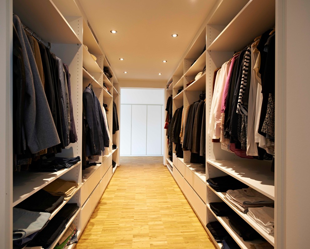 This is an example of a large contemporary gender-neutral walk-in wardrobe in Stuttgart with open cabinets, bamboo floors and beige floor.