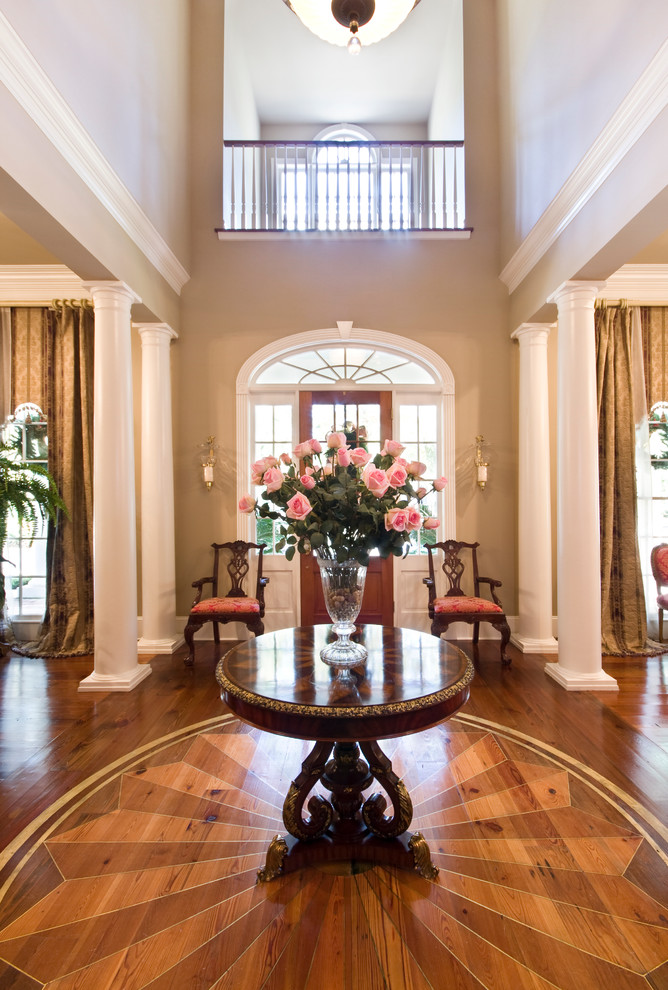 Photo of an expansive traditional foyer in New Orleans with beige walls, medium hardwood floors, a single front door and a medium wood front door.