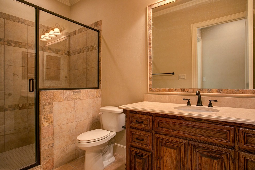 Mid-sized traditional 3/4 bathroom in Dallas with recessed-panel cabinets, medium wood cabinets, an alcove shower, a two-piece toilet, beige tile, ceramic tile, beige walls, travertine floors, an undermount sink, soapstone benchtops, beige floor and a hinged shower door.