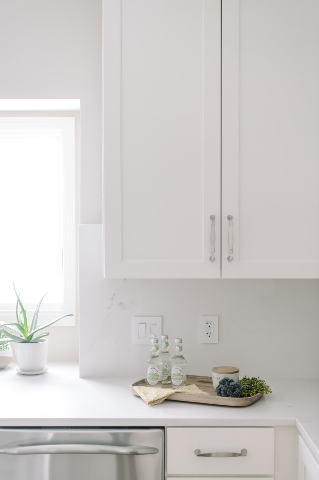 Example of a large transitional l-shaped laminate floor and brown floor eat-in kitchen design with an undermount sink, shaker cabinets, white cabinets, quartz countertops, white backsplash, quartz backsplash, stainless steel appliances, an island and white countertops