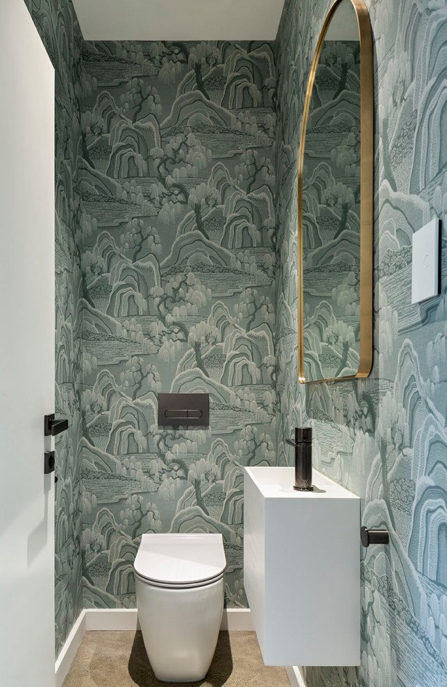 Aménagement d'un petit WC et toilettes contemporain avec des portes de placard blanches, WC à poser, un mur bleu, sol en béton ciré, un sol gris, meuble-lavabo suspendu et du papier peint.