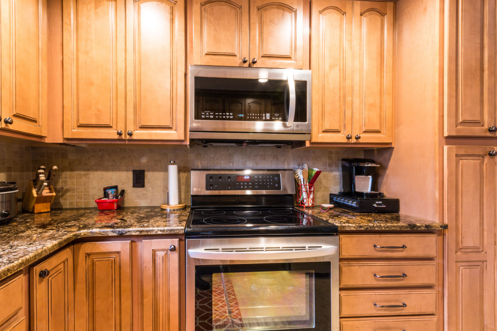 Example of a mid-sized u-shaped cement tile floor and beige floor eat-in kitchen design with an undermount sink, raised-panel cabinets, medium tone wood cabinets, granite countertops, stainless steel appliances, no island and brown countertops