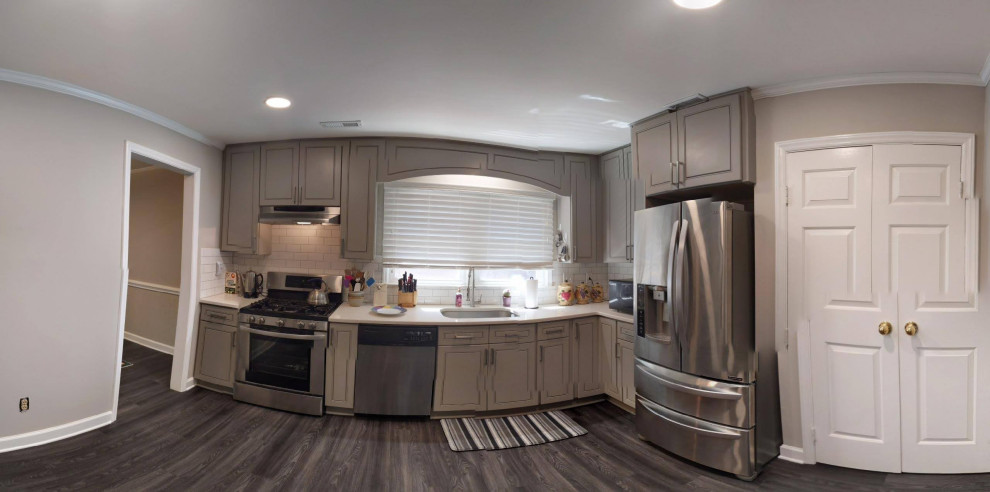Foto på ett mellanstort funkis vit l-kök, med en undermonterad diskho, luckor med profilerade fronter, grå skåp, bänkskiva i kvartsit, vitt stänkskydd, stänkskydd i tunnelbanekakel, rostfria vitvaror, laminatgolv och grått golv