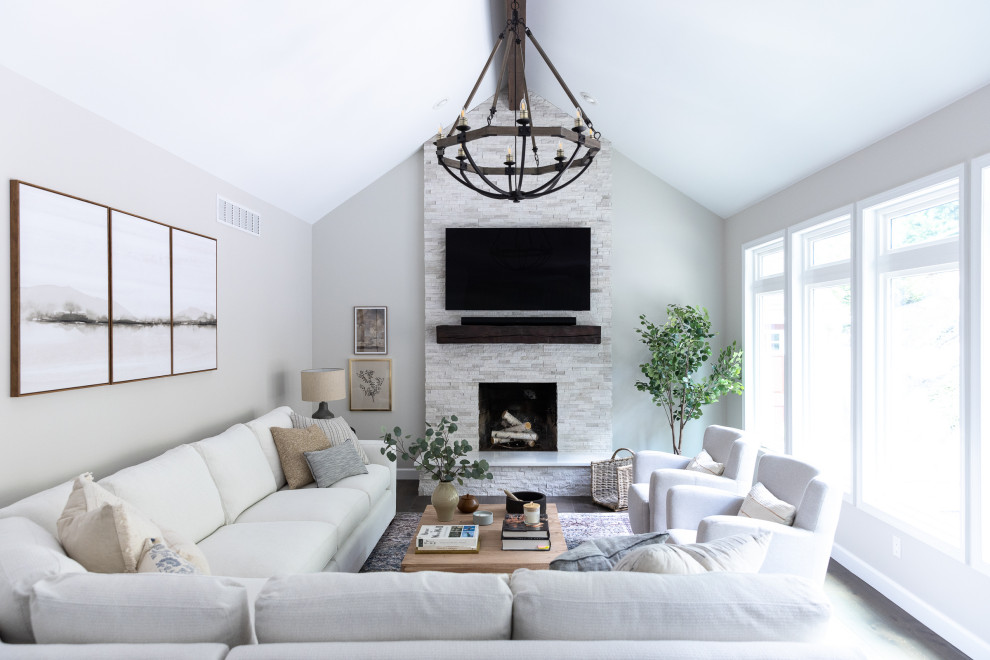 Inspiration for a large transitional open concept medium tone wood floor, brown floor and exposed beam living room remodel in Philadelphia with gray walls, a standard fireplace, a stacked stone fireplace and a wall-mounted tv