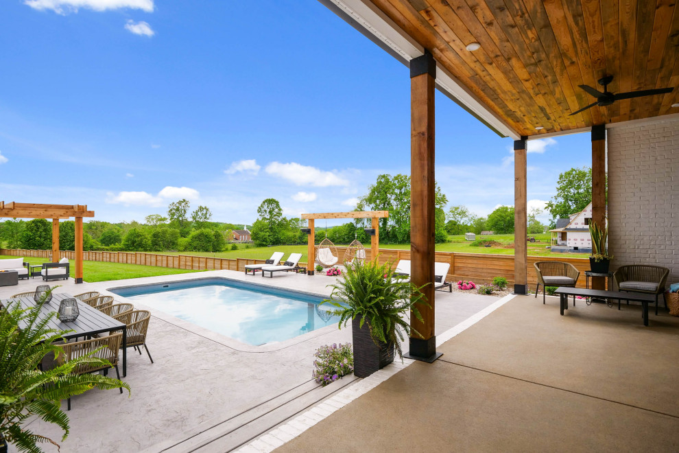 Ejemplo de piscina de estilo de casa de campo grande rectangular en patio trasero con adoquines de piedra natural