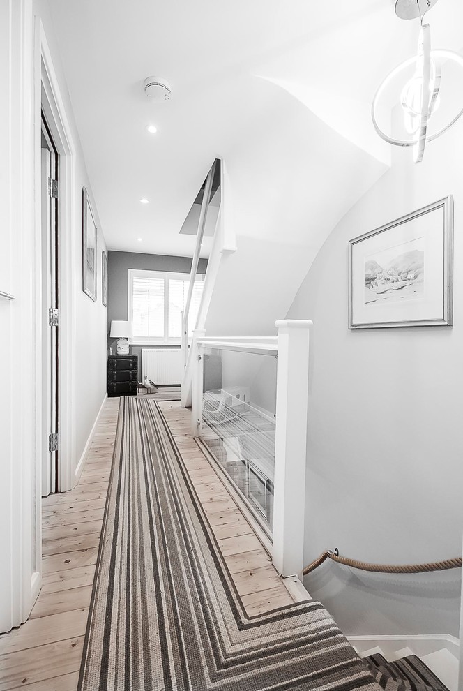 Design ideas for a mid-sized eclectic carpeted straight staircase in London with carpet risers and glass railing.