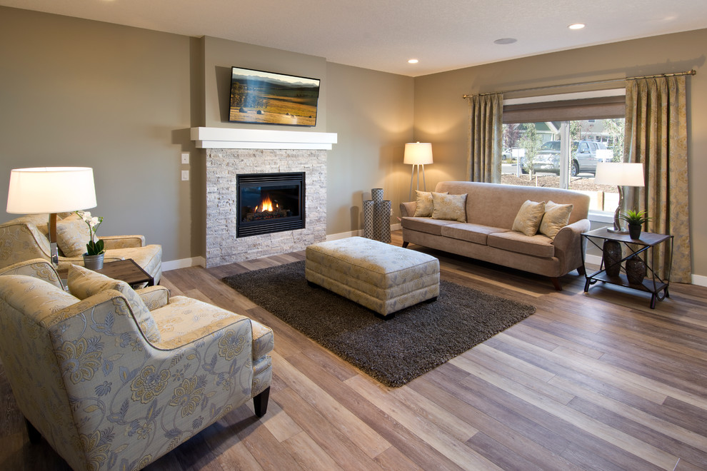 Photo of a large modern open concept living room in Calgary with brown walls, a wall-mounted tv, medium hardwood floors, a standard fireplace and a stone fireplace surround.