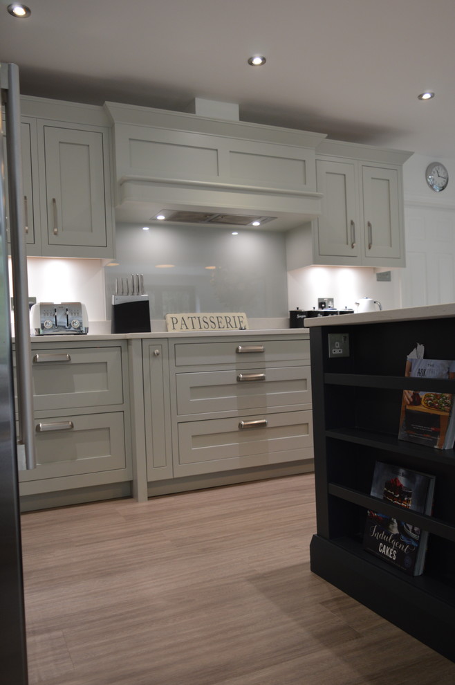 This is an example of a large traditional l-shaped open plan kitchen in Essex with an undermount sink, shaker cabinets, grey cabinets, quartzite benchtops, grey splashback, glass sheet splashback, stainless steel appliances, vinyl floors and with island.