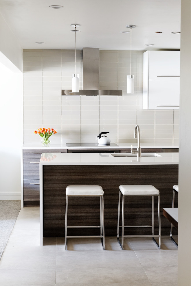 Photo of a mid-sized modern galley kitchen in Denver with flat-panel cabinets, white splashback, an undermount sink, solid surface benchtops, stainless steel appliances, with island, porcelain floors, glass tile splashback and dark wood cabinets.