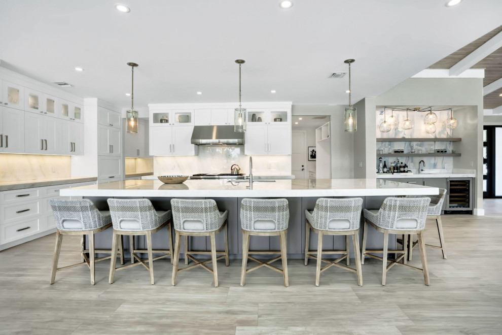 Inspiration for a large beach style l-shaped open plan kitchen in Miami with an undermount sink, shaker cabinets, white cabinets, white splashback, engineered quartz splashback, stainless steel appliances, porcelain floors, with island, grey floor, beige benchtop, timber and marble benchtops.