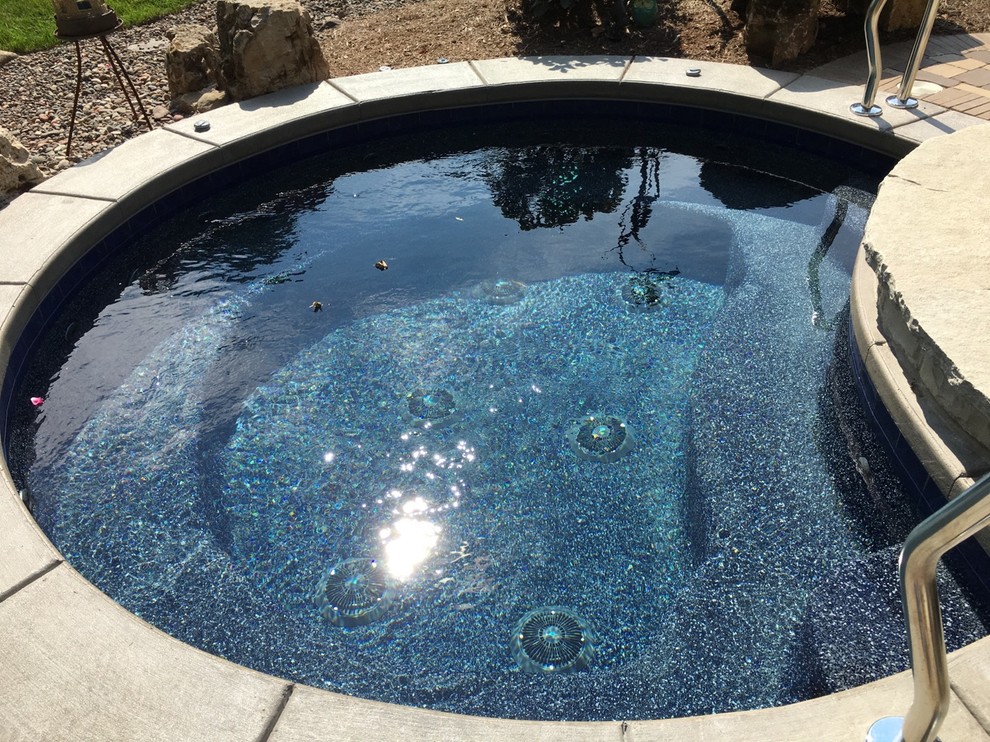 This is an example of a small traditional side yard round natural pool in Orlando with a water feature and brick pavers.