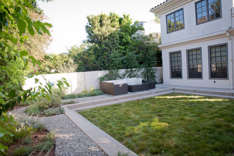 Mediterranean backyard partial sun xeriscape in Los Angeles with with lawn edging and gravel for winter.