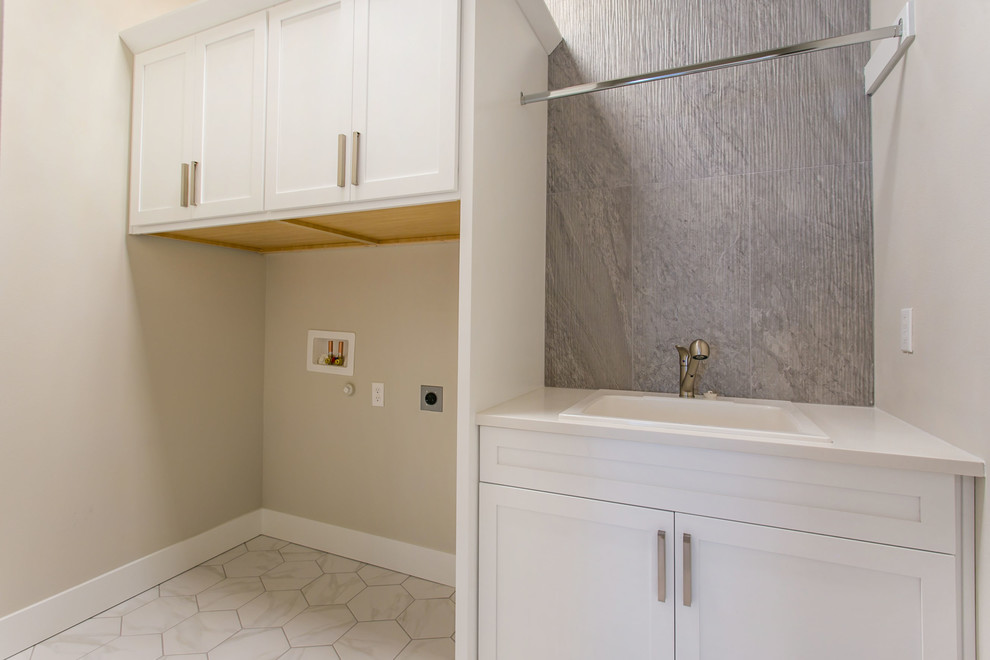 This is an example of a mid-sized single-wall dedicated laundry room in Seattle with an undermount sink, shaker cabinets, white cabinets, quartz benchtops, green walls, marble floors, a stacked washer and dryer, white floor and white benchtop.