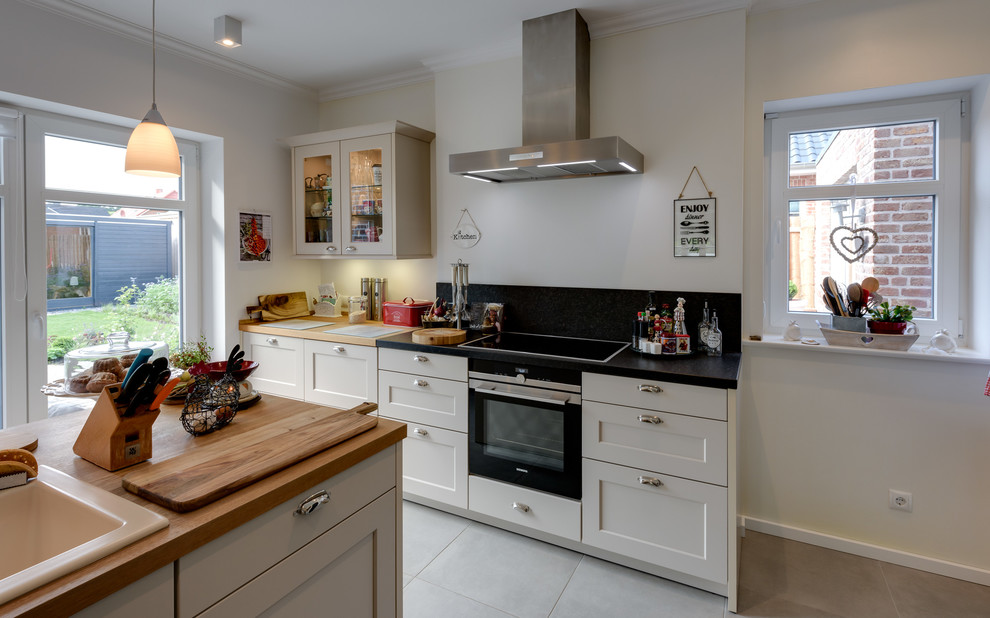 Exempel på ett mellanstort lantligt kök, med en rustik diskho, luckor med profilerade fronter, träbänkskiva, svart stänkskydd, stänkskydd i marmor, rostfria vitvaror, klinkergolv i keramik, en halv köksö, vita skåp och grått golv